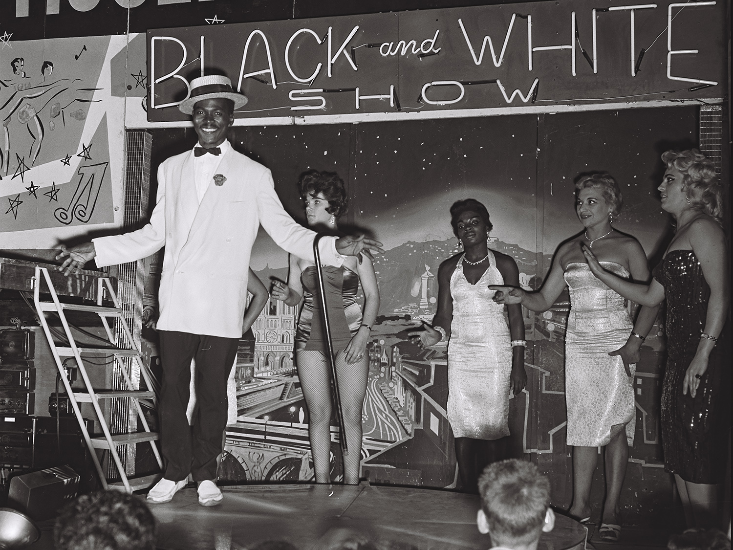 People in a stand, a sign behind them that says "Black and white show"