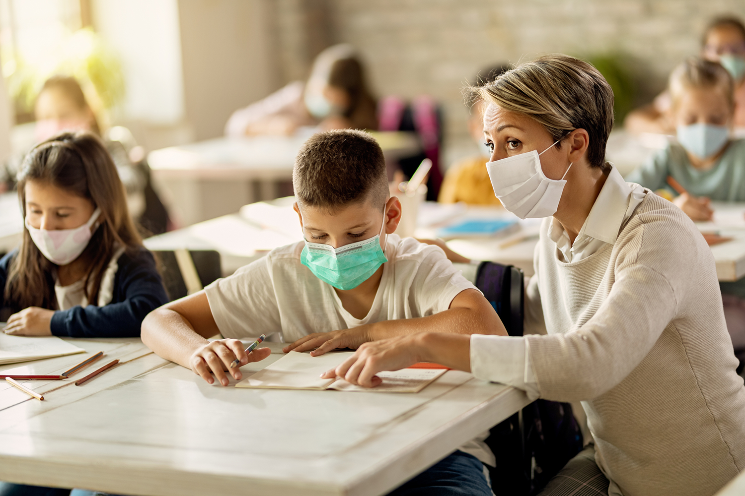 Lehrer und Schüler mit Masken im Klassenzimmer