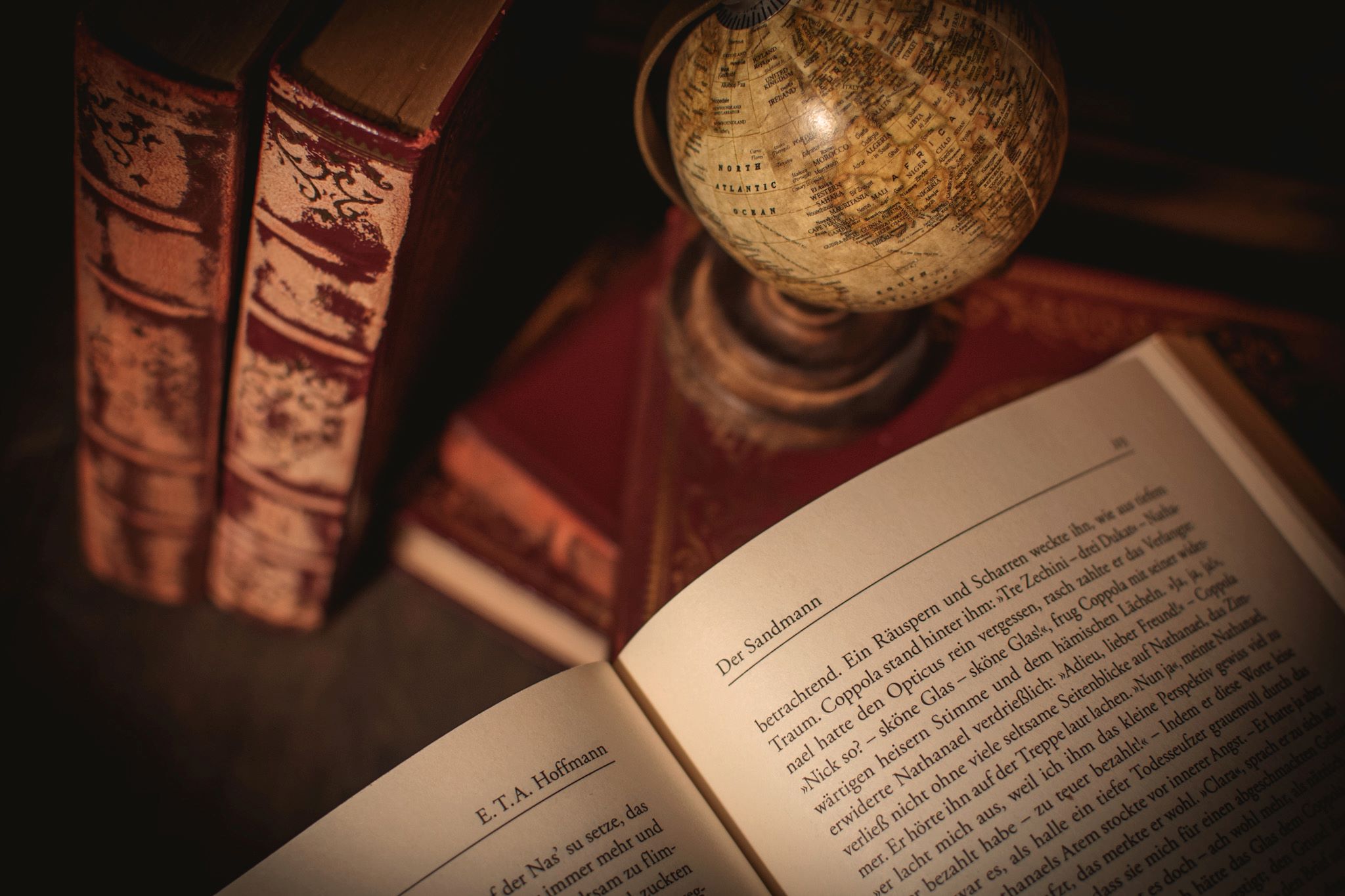 Book in German open on table with other books and a globe