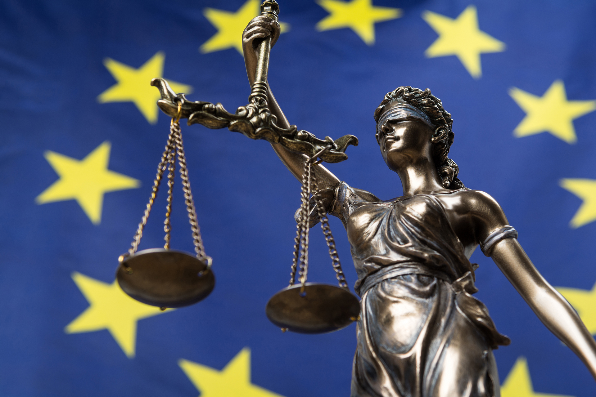 Statue of the blindfolded goddess of justice Themis or Justitia, against an European flag