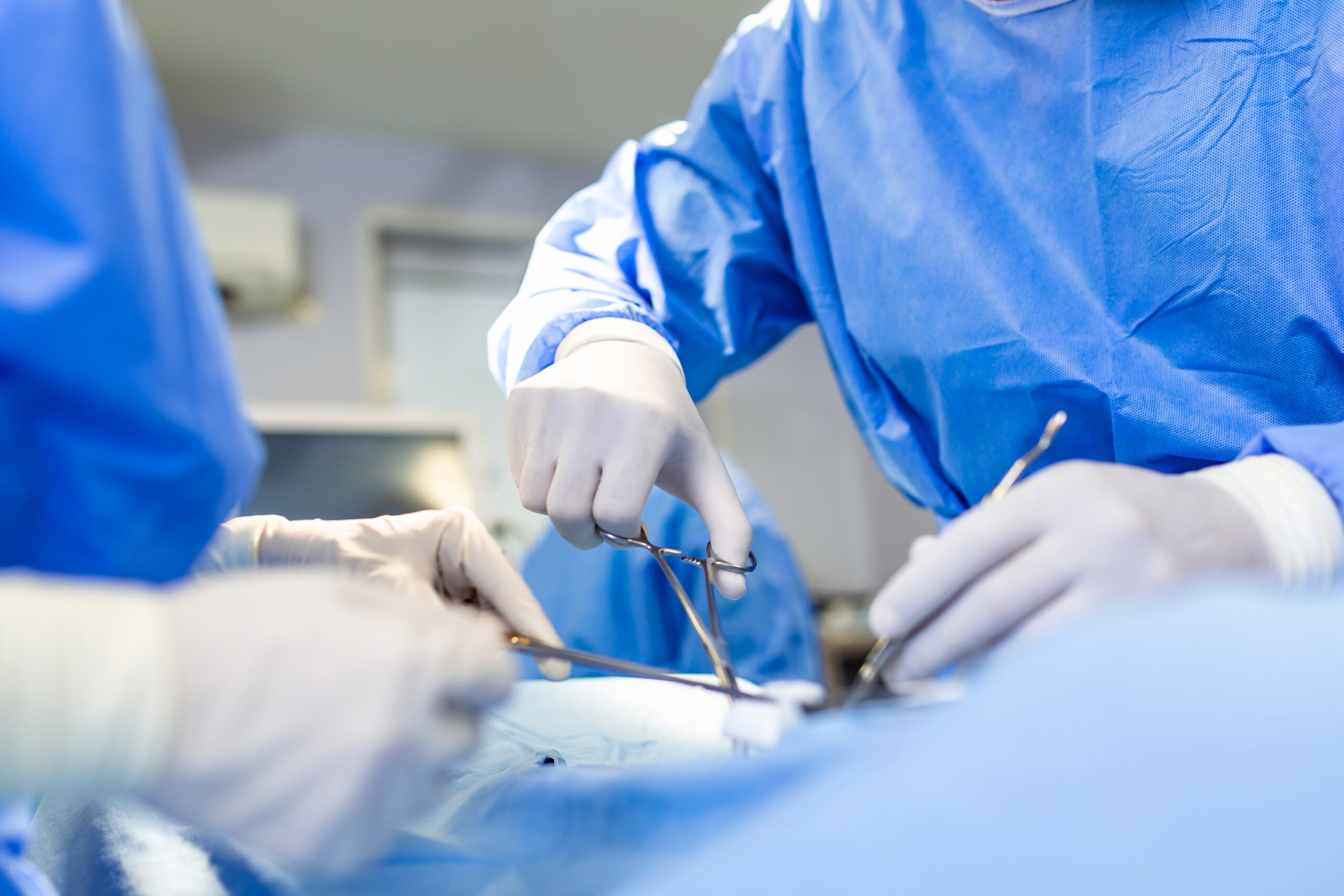 Surgery operation. Group of surgeons in operating room with surgery equipment. Medical background, selective focus. Surgeon team working together while operation