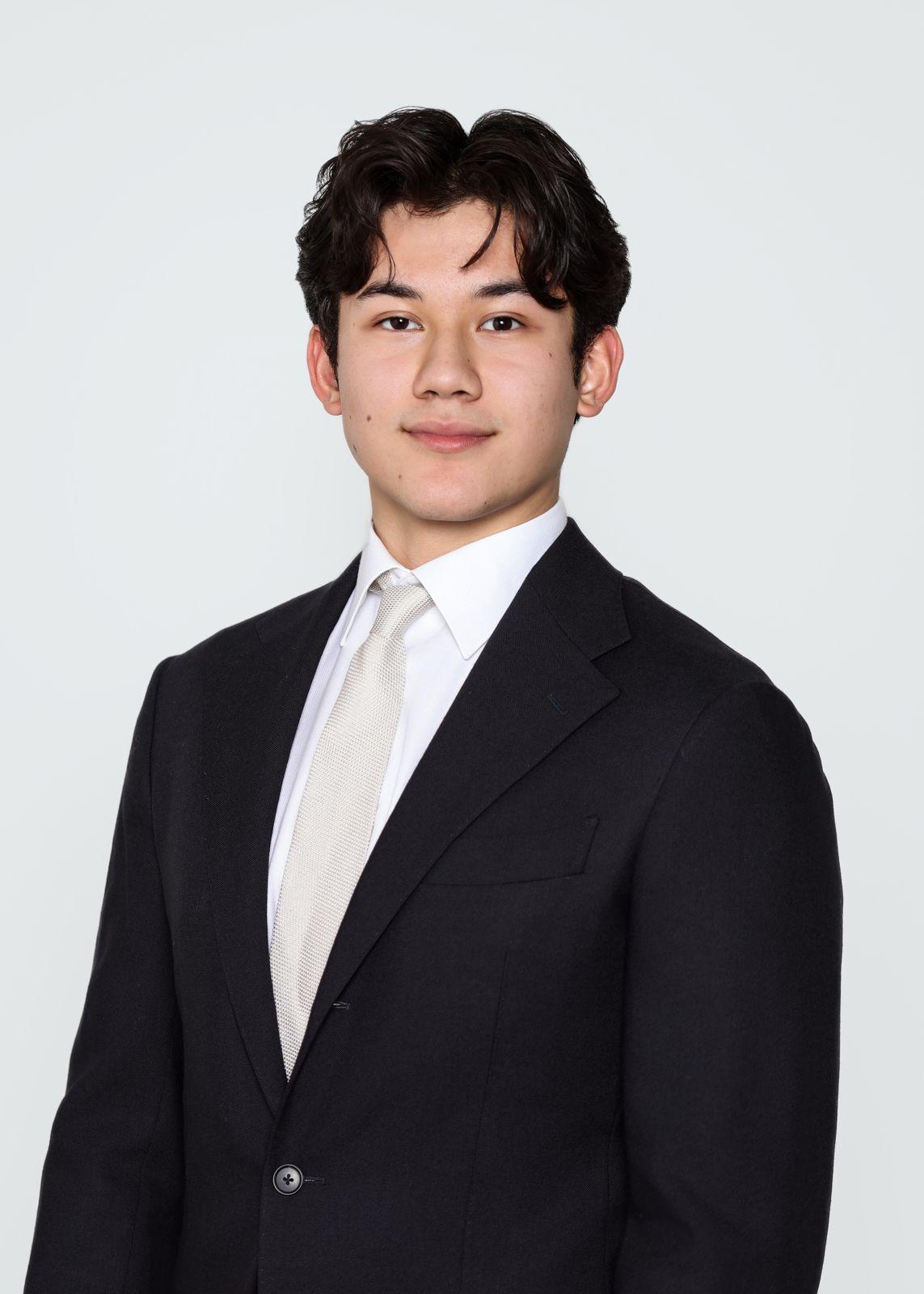 Portrait of Anthony Stassart, wearing a dark suit and light-colored shirt, smiling slightly against a neutral background