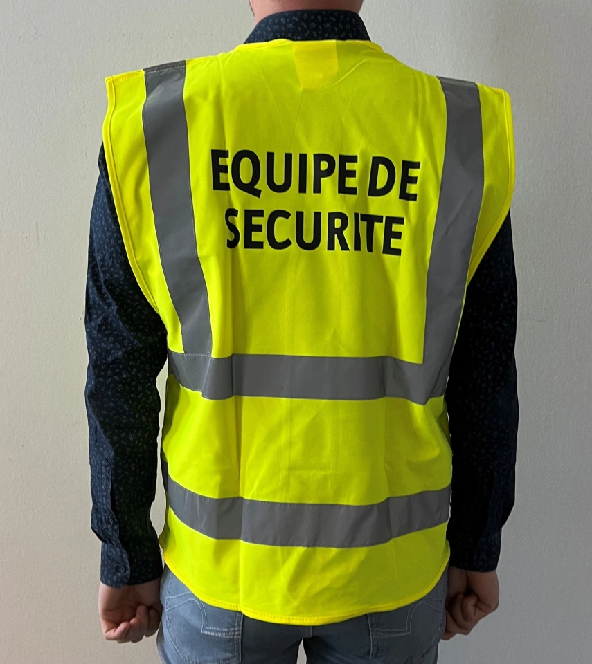 Person wearing a bright neon safety vest with the words "Equipe de securité" in French.